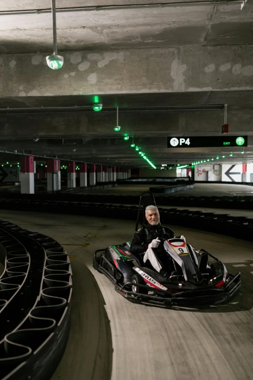 a person riding a go kart in a parking garage, happening, inside the tunnel, 8 0. lv, jenni pasanen, in an arena