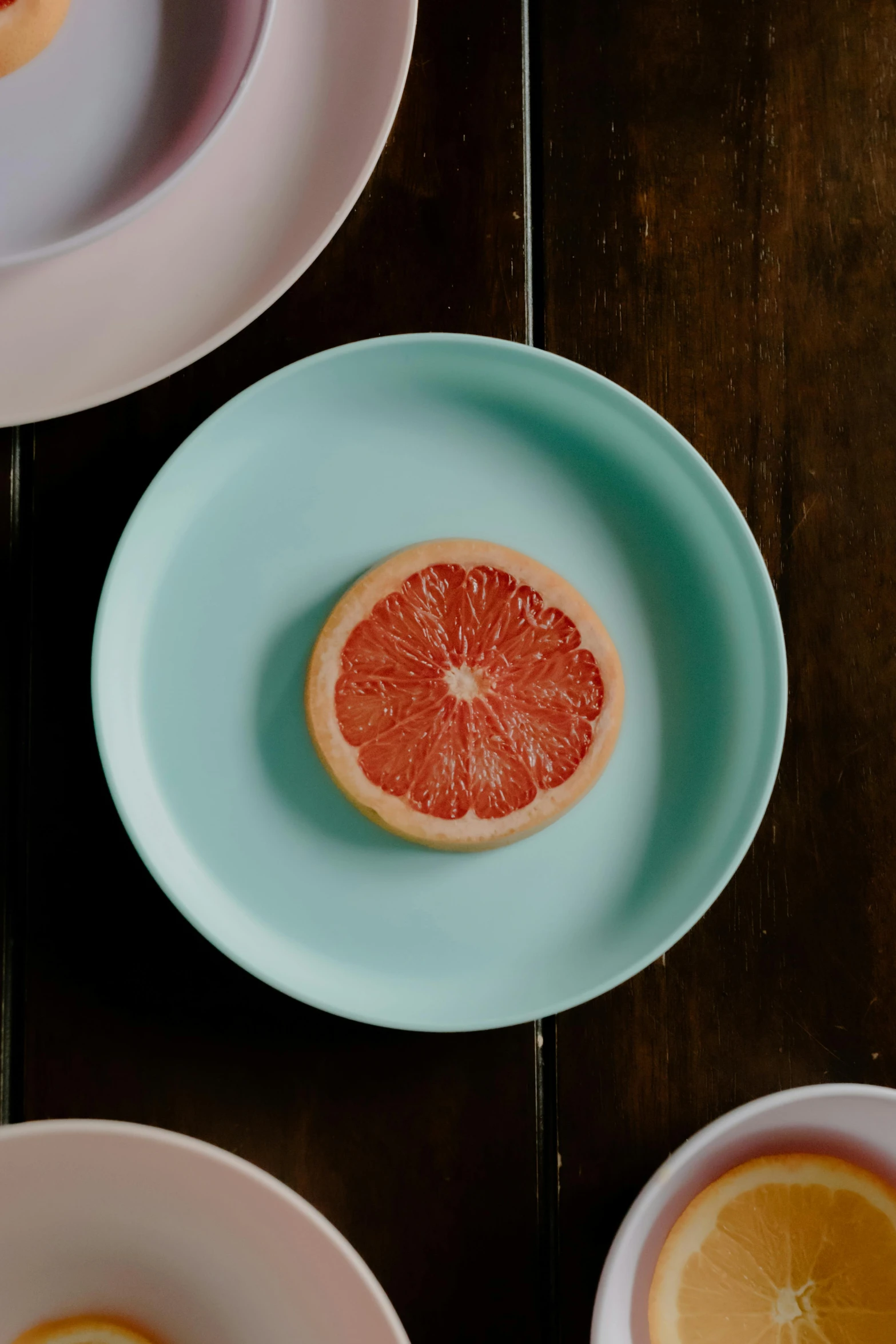 a table topped with plates filled with slices of grapefruit, a still life, unsplash, seafoam green, gal gadot china plate, matte surface, middle close up shot