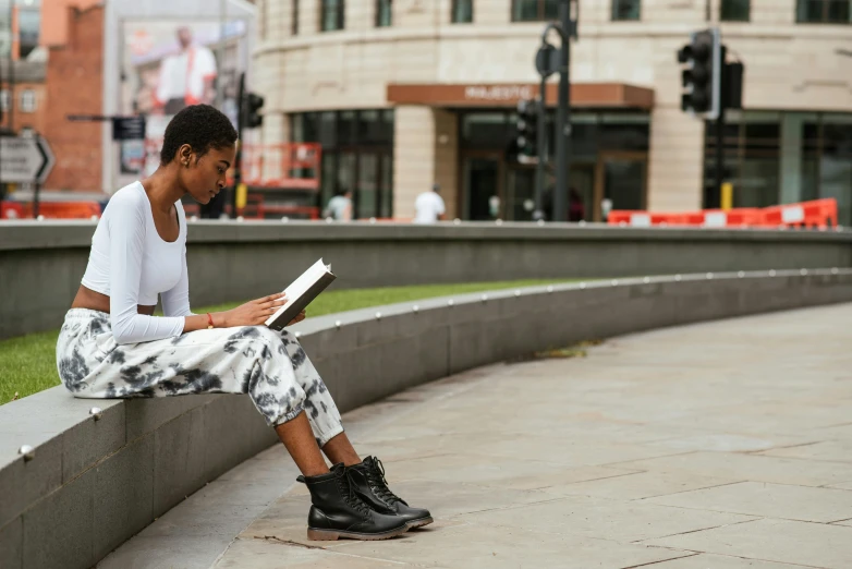 a man sitting on a ledge reading a book, pexels contest winner, realism, black teenage girl, london south bank, trying to study, sittin