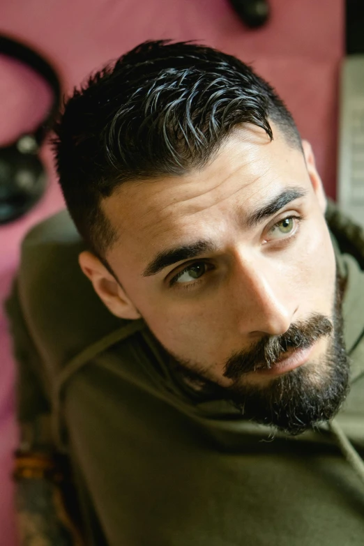 a man with a beard sitting in a chair, an album cover, trending on pexels, hurufiyya, androgynous face, f 1 driver charles leclerc, closeup headshot portrait, middle eastern