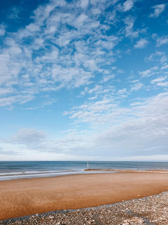 a bench sitting on top of a sandy beach next to the ocean, unsplash, minimalism, wispy clouds in a blue sky, maryport, thumbnail, omaha beach