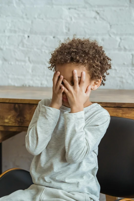 a little boy sitting at a desk with his hands on his face, light skinned african young girl, when it's over, embarrassing, with textured hair and skin