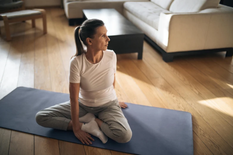 a woman sitting on a yoga mat in a living room, by Elizabeth Durack, pexels contest winner, plain stretching into distance, profile image, manuka, avatar image