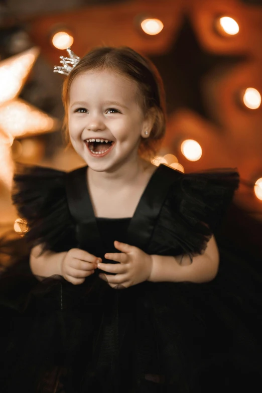 a little girl standing in front of a christmas tree, a portrait, pexels contest winner, black gown, both laughing, 256435456k film, dasha taran