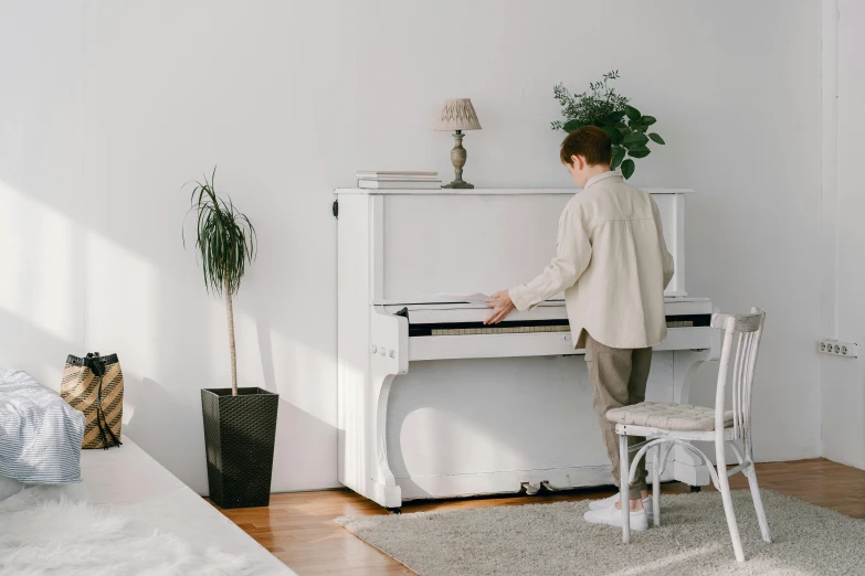 a man standing next to a white piano in a living room, trending on pexels, kawai, profile image, fan favorite, full lenght view. white plastic