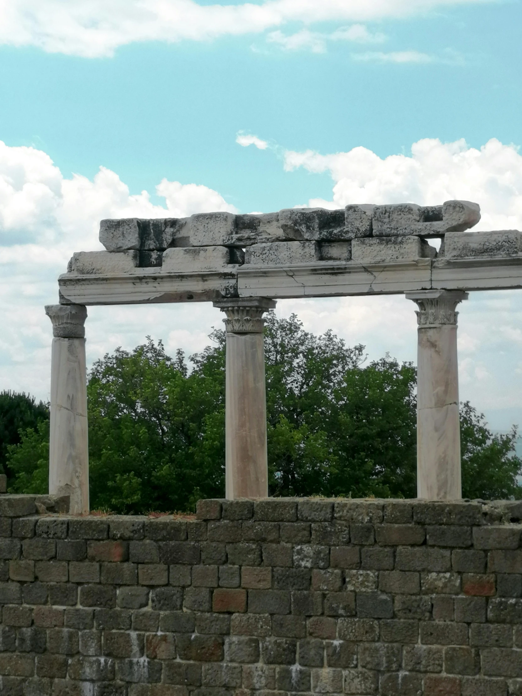 a stone structure sitting on top of a stone wall, inspired by Roman Bezpalkiv, neoclassicism, at the stone ruins, trending photo, greek-esque columns and ruins, but not pretty