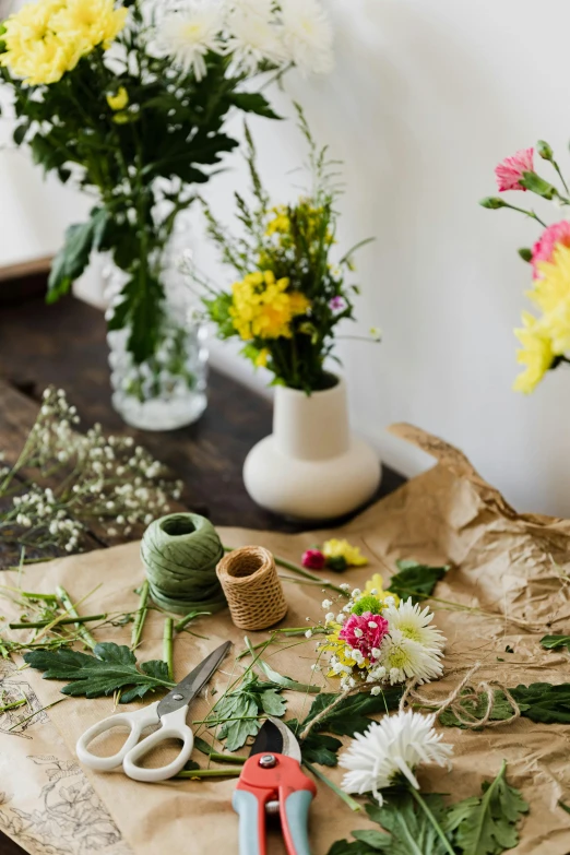 a bunch of flowers sitting on top of a table, a still life, trending on unsplash, arts and crafts movement, natural materials, wrapped in flowers and wired, indoor shot, gardening