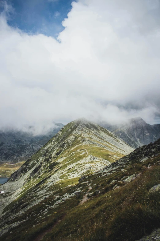 a mountain with a lake in the middle of it, looking downwards, carpathian mountains, under a gray foggy sky, rocky terrain