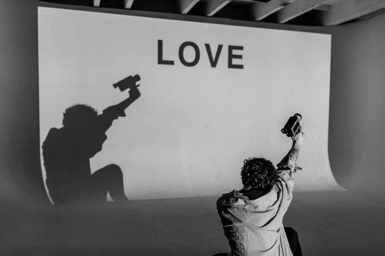 a black and white photo of a person holding a camera, by Giuseppe Avanzi, unsplash, graffiti, alec soth : : love, projection design installation, with pistol, love scene