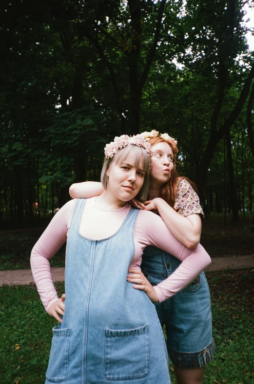 a couple of women standing next to each other, an album cover, inspired by Diane Arbus, unsplash, renaissance, flower crown, low quality photo, a park, scanned