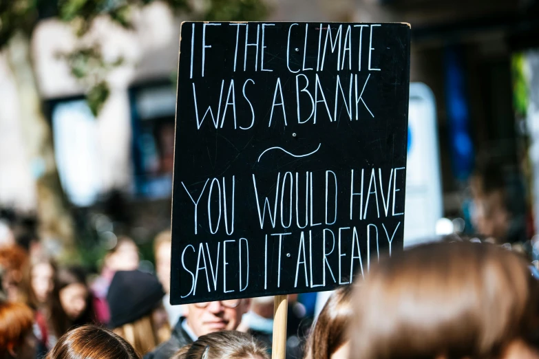 a sign that says if the climate was a bank you would have saved it already, a photo, by Julia Pishtar, trending on unsplash, protest, 15081959 21121991 01012000 4k, people outside walk, panel of black