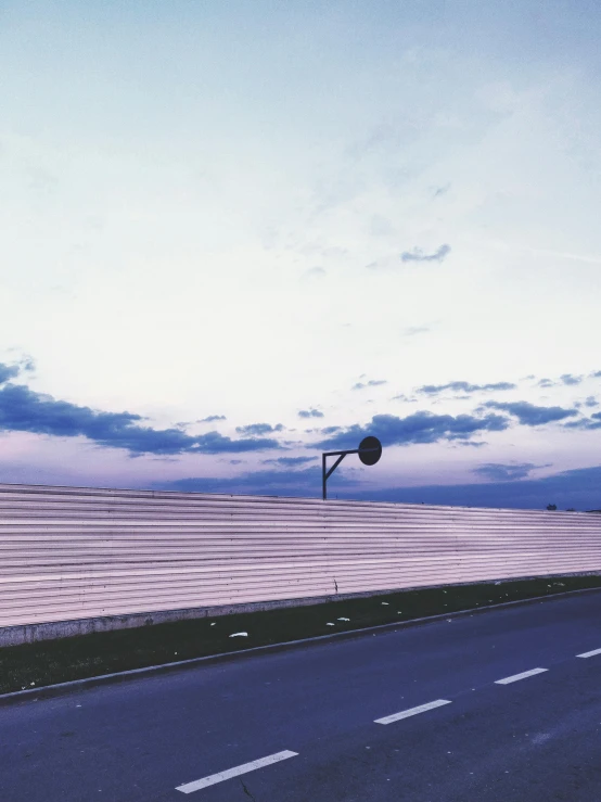 a street light sitting on the side of a road, an album cover, by Niko Henrichon, unsplash, postminimalism, the sky is pink, guardrails, panoramic view, outdoor art installation