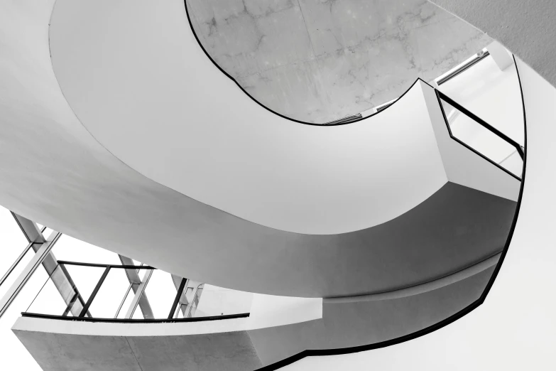 a black and white photo of a spiral staircase, inspired by Ned M. Seidler, unsplash contest winner, minimalism, concrete hitech interior, frank gehry, white walls, high ceiling