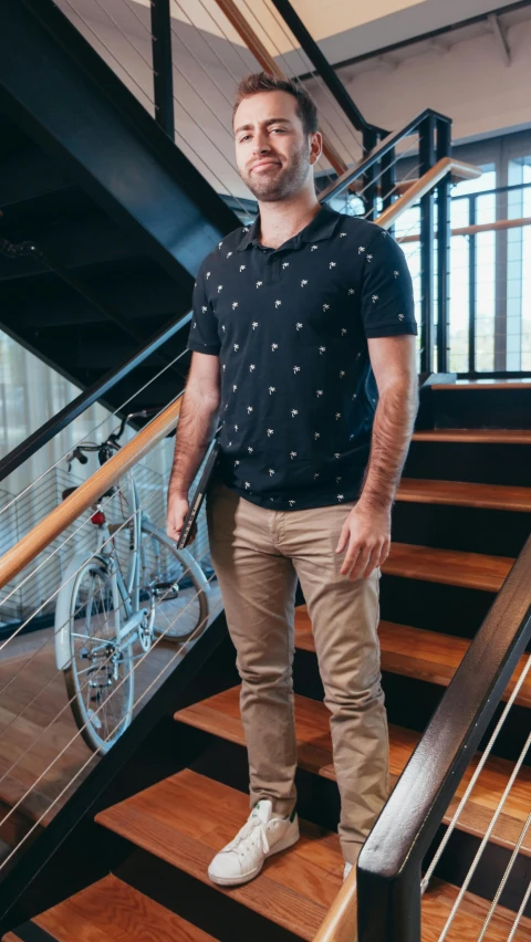 a man standing at the bottom of a flight of stairs, pexels contest winner, wearing polo shirt, bicycle, rhett and link, intricate details. front on