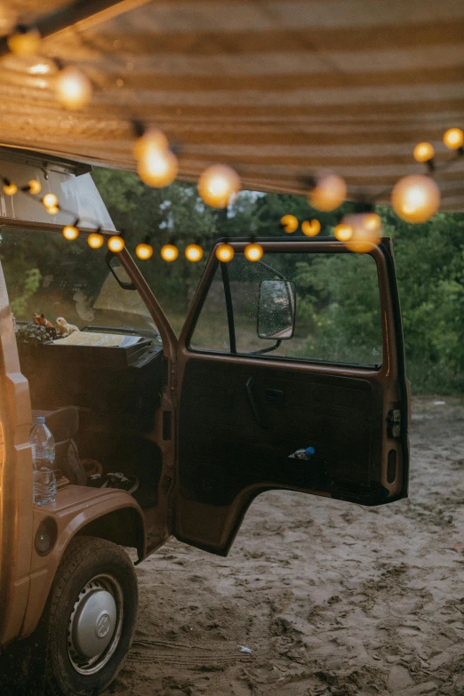 a couple of people sitting in the back of a truck, unsplash contest winner, renaissance, tea drinking and paper lanterns, kombi, cabin lights, brown