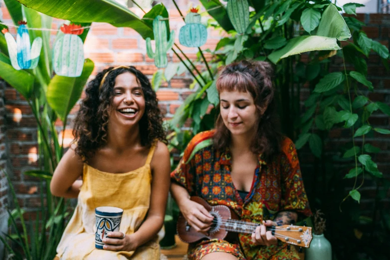 two women sitting next to each other playing guitars, pexels contest winner, antipodeans, tropical houseplants, laughing bear musician, plants and patio, coffee and musical instrument