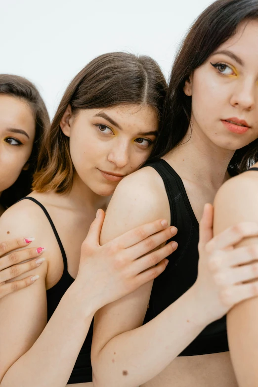 a group of young women standing next to each other, by Julia Pishtar, trending on pexels, antipodeans, synthetic bio skin, hands crossed, dewy skin, with a white background