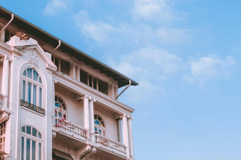a white building with lots of windows and balconies, a photo, pexels contest winner, neoclassicism, colombo sri lankan city street, the sky is pink, profile image, at the terrace