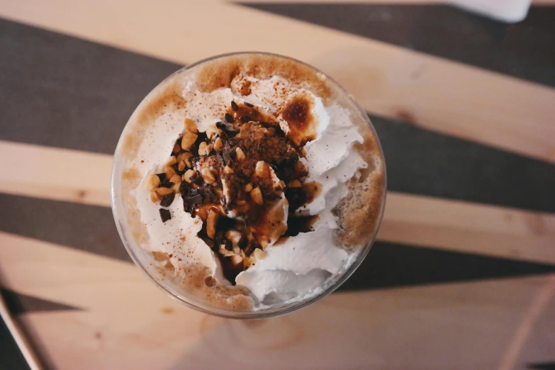 a close up of a cup of coffee on a table, whipped cream, food, thumbnail, dessert