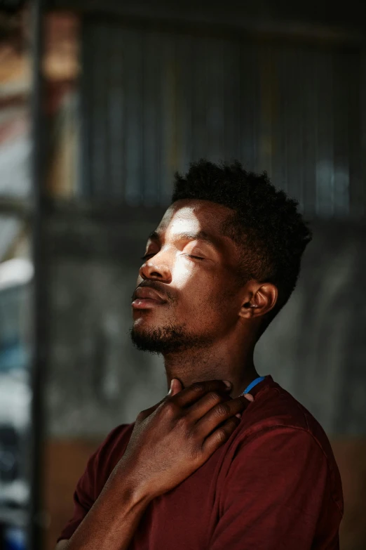 a man standing in front of a building with his eyes closed, inspired by Gordon Parks, trending on pexels, with brown skin, thin young male, in a sunbeam, 2 1 savage
