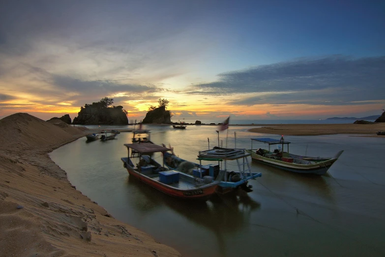 a group of boats sitting on top of a sandy beach, by Basuki Abdullah, unsplash contest winner, sumatraism, beside a river, sunset panorama, slide show, small port village