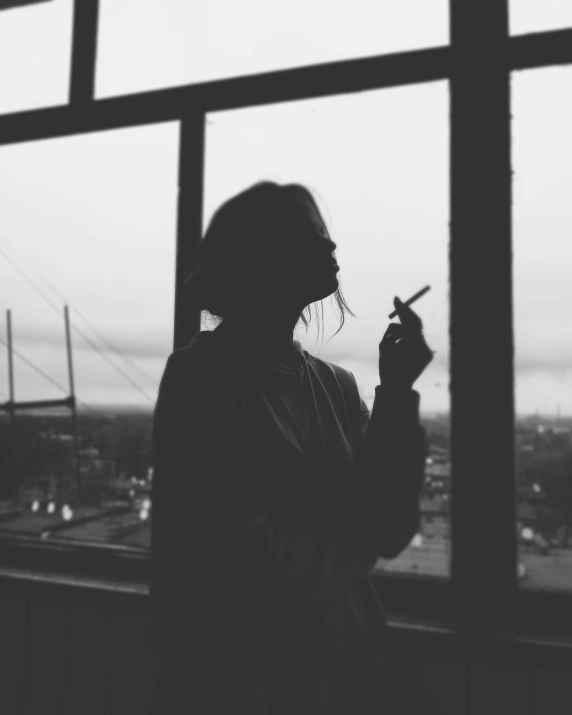 a woman smoking a cigarette in front of a window, a black and white photo, unsplash, silhouette :7, girl standing, on rooftop, ✨🕌🌙