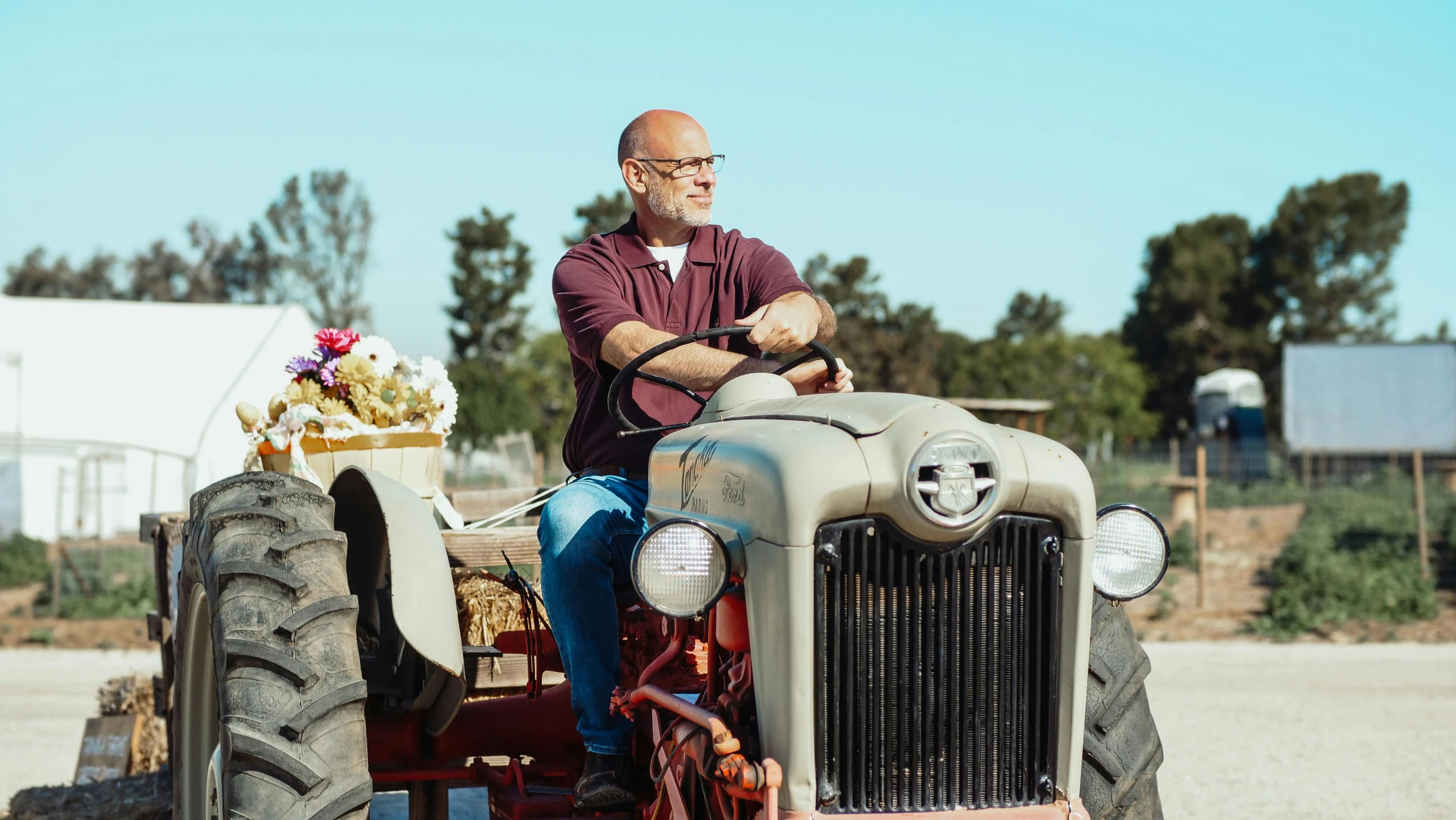 a man that is sitting on a tractor, a portrait, by Edward Avedisian, unsplash, renaissance, bald head, parade floats, still image from tv series, hollister ranch