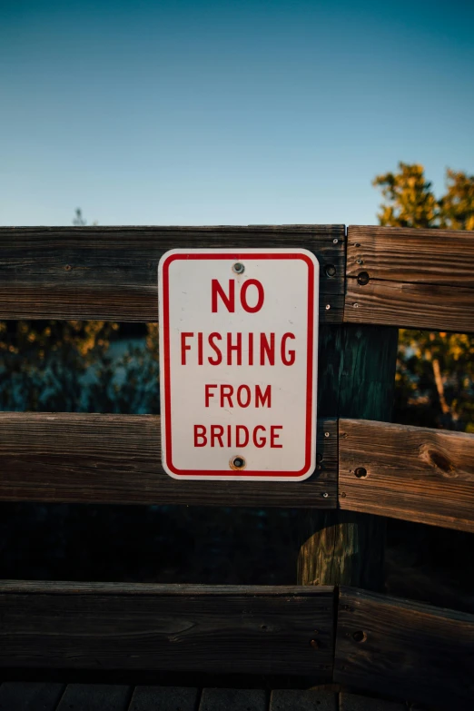 a no fishing from bridge sign on a wooden fence, by Niko Henrichon, unsplash, lots of bridges, 2022 photograph, shady, bryan skerry