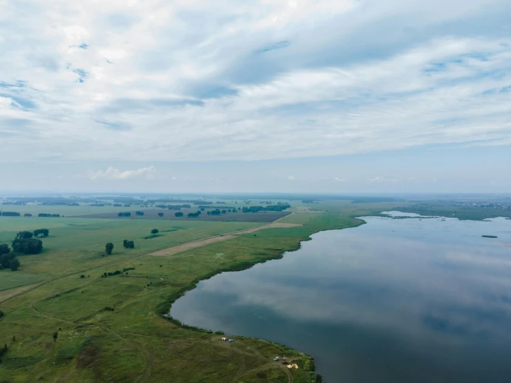 a large body of water sitting on top of a lush green field, by Daniel Lieske, hurufiyya, sky - high view, high quality photo, grey, floodplains