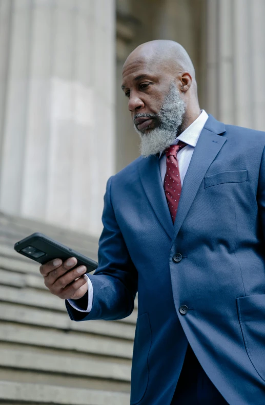 a man in a blue suit holding a cell phone, gray hair and beard, black man, mobile app, taken in 2 0 2 0