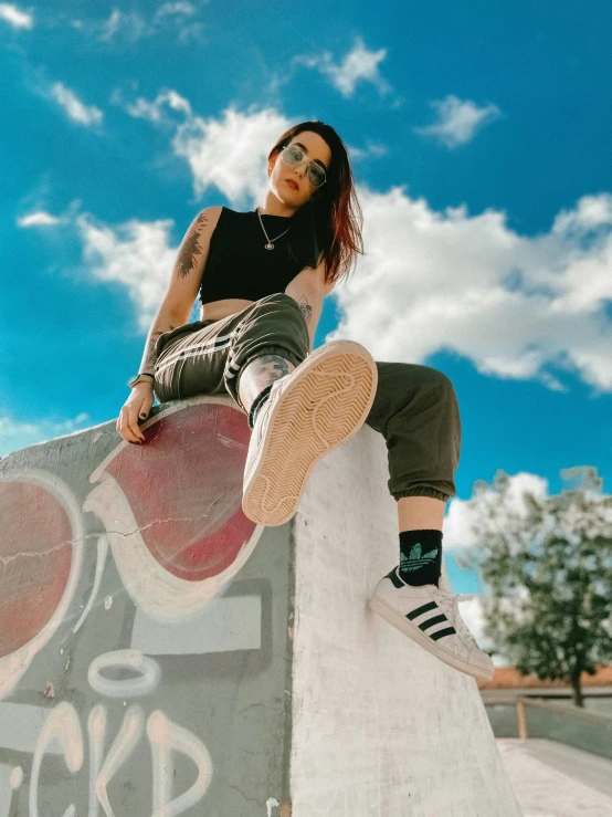 a woman sitting on top of a cement wall, inspired by Ion Andreescu, trending on pexels, graffiti, high soles, avatar image, in the sky, wearing adidas clothing