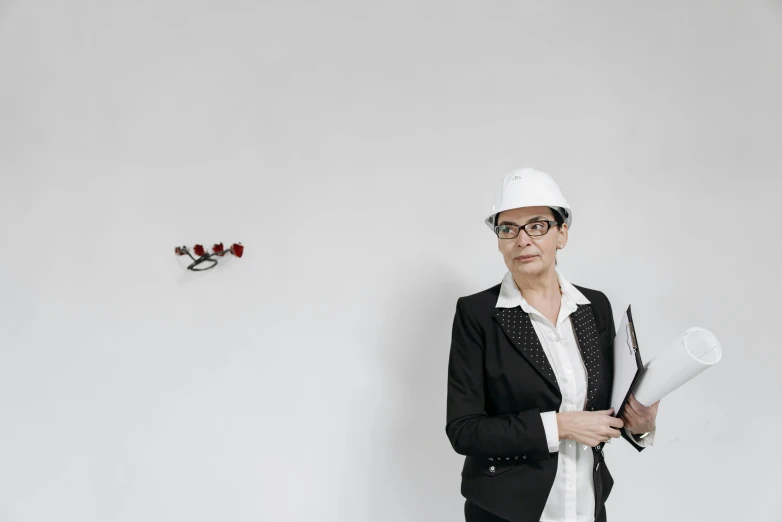 a woman in a hard hat holding a piece of paper, an album cover, by Jan Kupecký, arbeitsrat für kunst, wearing a suit and glasses, drones, in white room, profile image