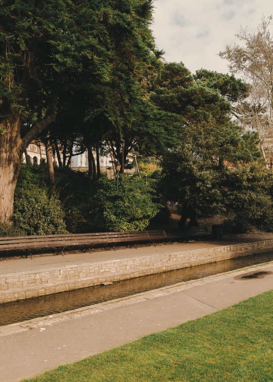 a man riding a skateboard down a sidewalk next to a river, a picture, inspired by Richmond Barthé, unsplash, renaissance, grassy knoll, staggered terraces, england, tan