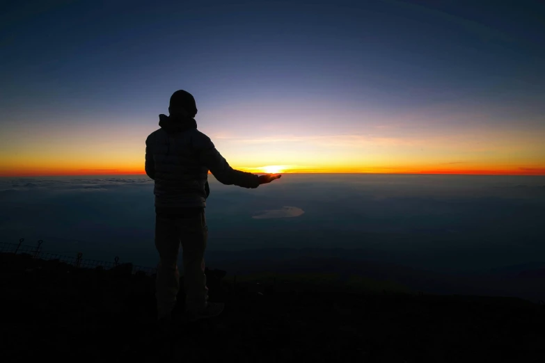 a man standing on top of a mountain at sunset, a picture, in volcano, ((sunset)), yan gisuka, praying