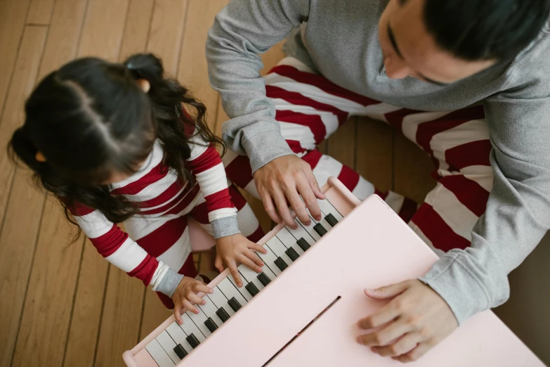 a man and a little girl playing with a pink piano, pexels contest winner, wearing pajamas, red and white color scheme, avatar image, top - down photo