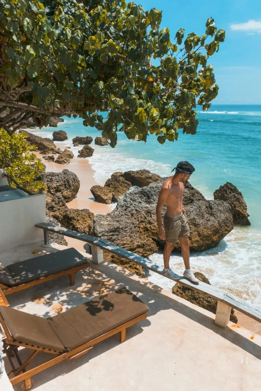 a man standing on top of a beach next to the ocean, lush garden surroundings, stone steps, beaching, bali