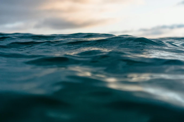 a close up of a body of water with clouds in the background, a picture, by Daniel Lieske, unsplash, ocean swells, shallow depth of fielf, lit from bottom, detailed photo 8 k