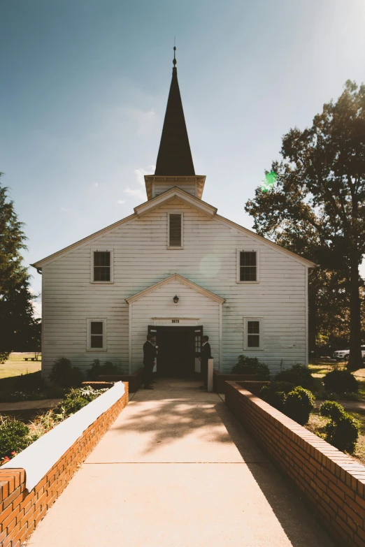 a white church with a steeple on a sunny day, a photo, unsplash, sunfaded, full front view, rural, multiple stories