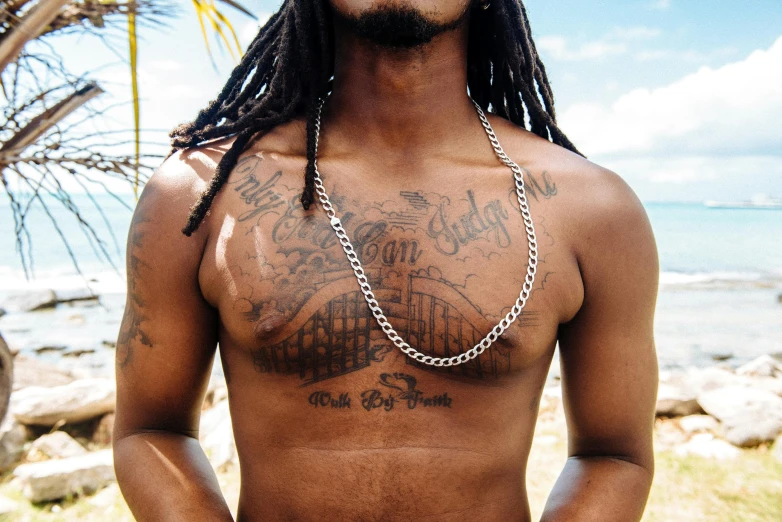 a man with a chain around his neck, a tattoo, trending on pexels, caribbean, alternate album cover, shot in 35mm, upper body image
