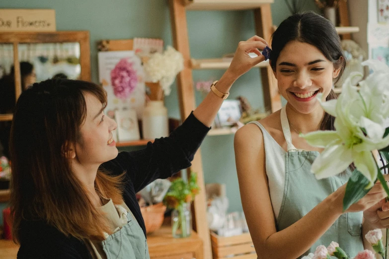 a woman combing another woman's hair in a flower shop, pexels contest winner, arts and crafts movement, avatar image, starbucks aprons and visors, happy friend, indi creates