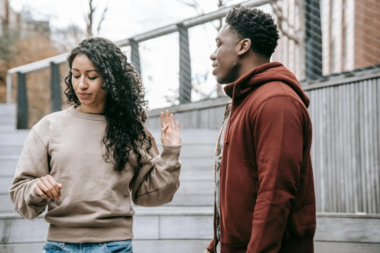 a man and a woman standing next to each other, trending on pexels, black teenage boy, arguing, brown curly hair, half turned around