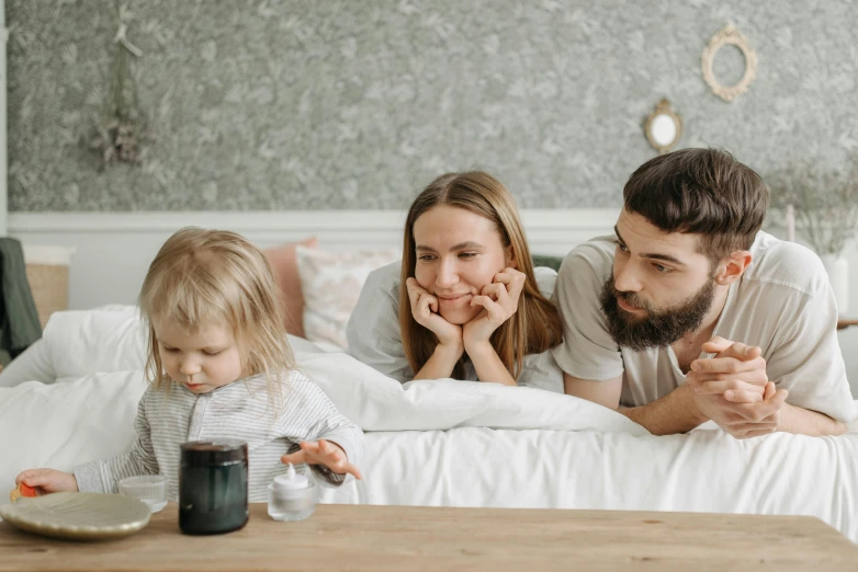 a man and woman laying in bed with a little girl, pexels contest winner, watching tv, avatar image, drinking cough syrup, people looking at a house