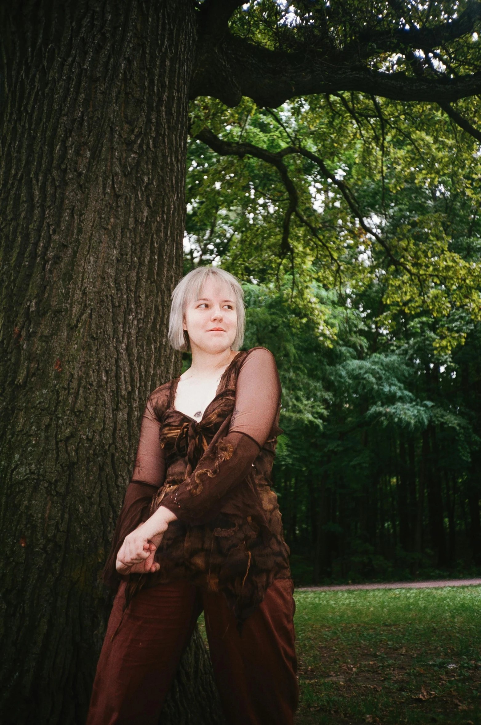 a woman leaning against a tree in a park, an album cover, by Attila Meszlenyi, portrait image, pale hair, full frame image, taken in the 2000s