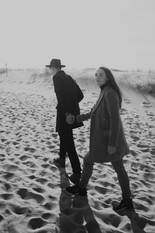 a man and a woman walking on a beach, a black and white photo, by Felix-Kelly, “portrait of leonard cohen, roots and hay coat, ✨🕌🌙, lofi