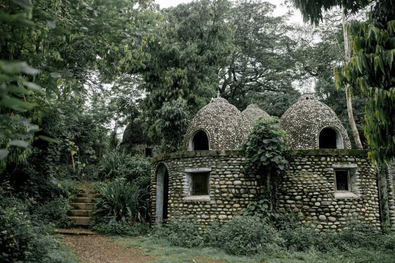 a stone building sitting in the middle of a forest, inspired by Théodore Rousseau, renaissance, tribe huts in the jungle, white stone arches, jamaica, houses in the shape of mushrooms