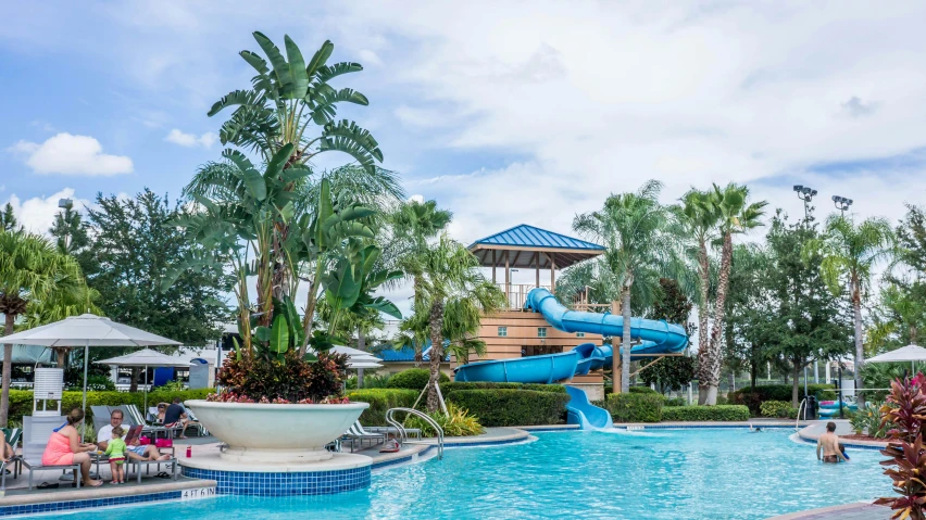 a large pool with a water slide in the middle of it, pexels contest winner, tree palms in background, avatar image, disney world, kids place