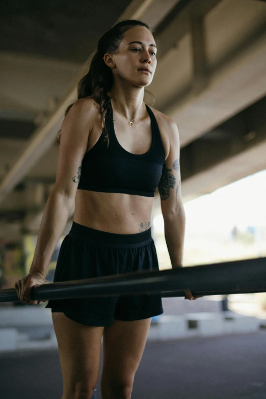 a woman holding a baseball bat under a bridge, detailed sports bra, in a gym, promo image, profile image