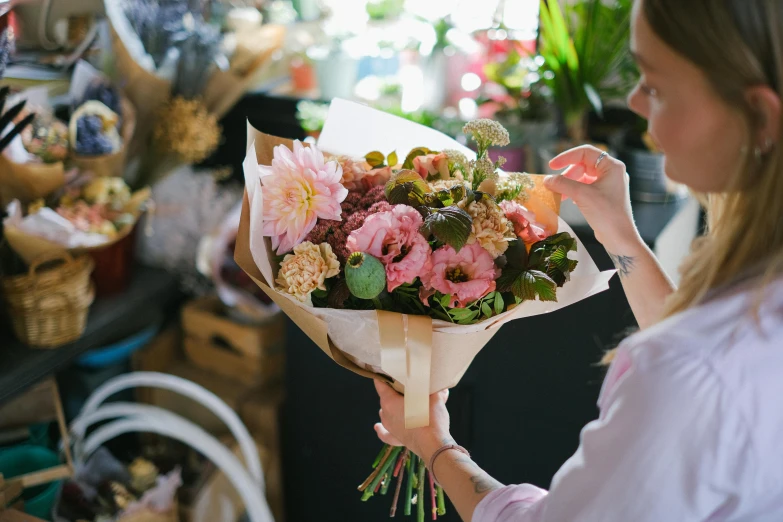 a woman holding a bunch of flowers in her hands, botanicals, pinks, with a bunch of stuff, back towards camera