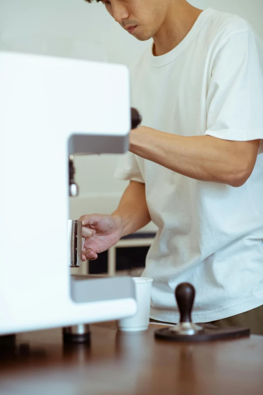 a man that is standing in front of a computer, by Yasushi Sugiyama, unsplash, private press, coffee machine, wearing an apron, white sleeves, dynamic closeup