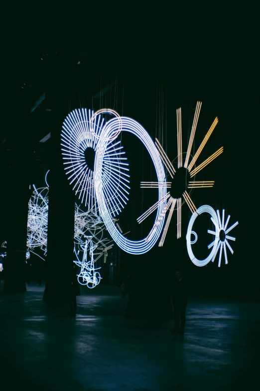 a group of people standing on top of a stage, by Cerith Wyn Evans, unsplash, kinetic art, with glow on some of its parts, portals, suns, with a black dark background